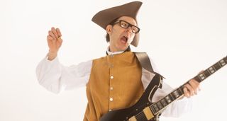 Paul Gilbert wears a tricorn hat and tan button-up waistcoat as he embraces the Washingtonian aesthetic with his signature Ibanez Fireman.