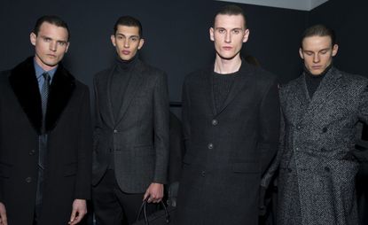 Four male models stood side by side in black outfits