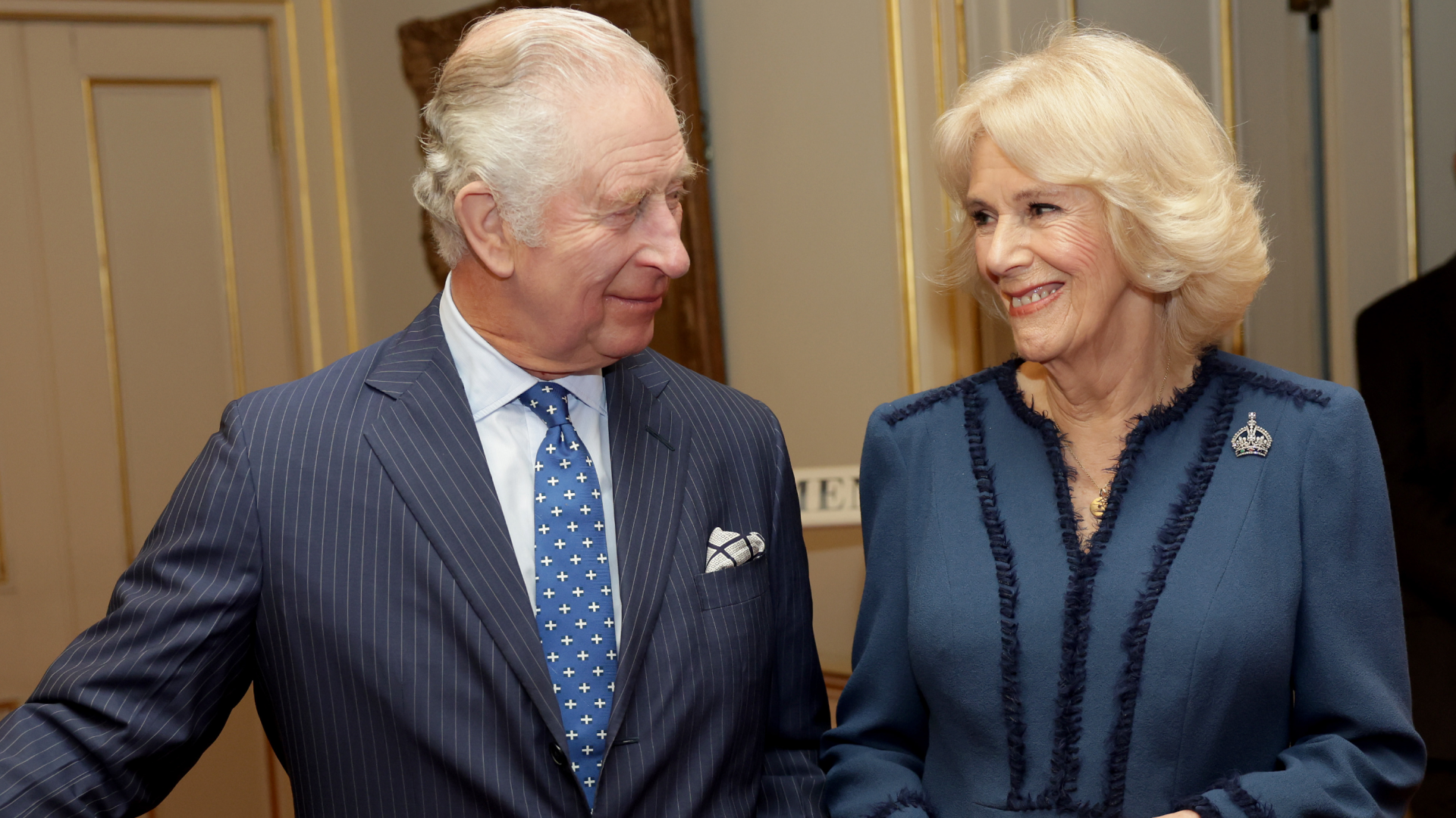 King Charles and Queen Camilla smiling at each other in blue outfits