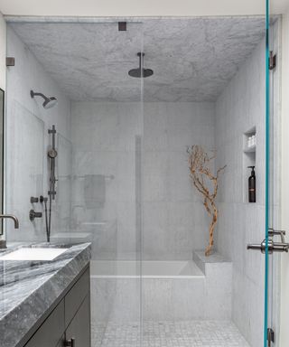 Bathroom with walk in tiled shower with marble tiles and glass screen, black bathroom cabinet with gray marble countertop