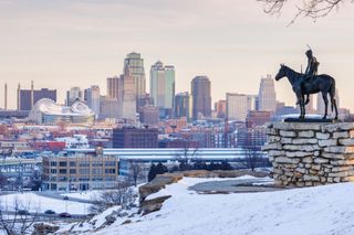 The Scout statue and Kansas City panorama at sunrise.