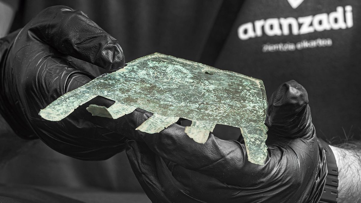 Researcher in black gloves holds a bronze hand-shaped amulet is thought to have been a good-luck charm.