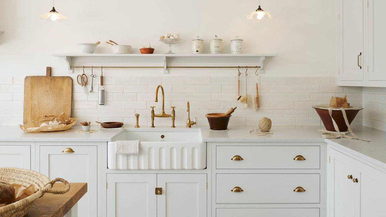 A light blue and white kitchen with marble countertops and brass hardware