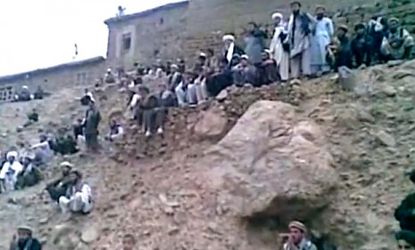 Afghan men stand on a hill moments before a Taliban judge shoots a woman to death, reportedly her punishment for alleged adultery.