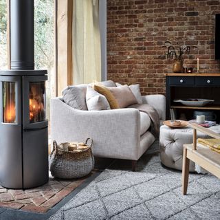 living room with wood burning stove, brick wall and grey sofa