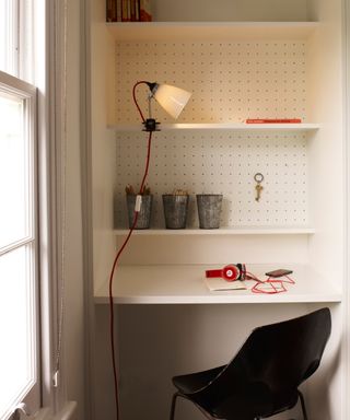 white pegboards on back wall of desk created in alcove