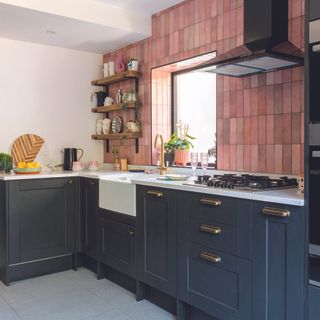 Navy shaker kitchen with white worktops and pink tiled wall.