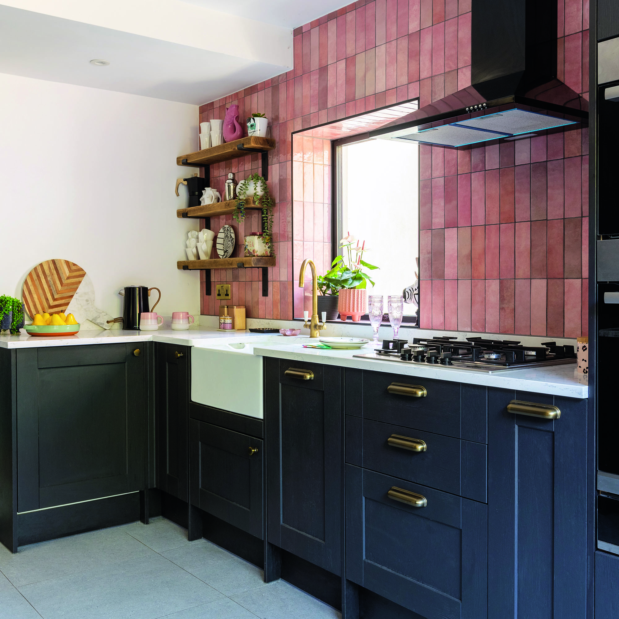 Navy shaker kitchen with white worktops and pink tiled wall.