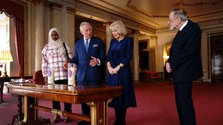 King Charles III and Camilla, Queen Consort light a candle at Buckingham Palace