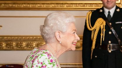 Queen in high spirits as she dons neon pink and green dress 