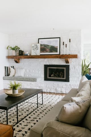 white living room with textural black and white rug fireplace in brick walls and wooden floating mantelpiece