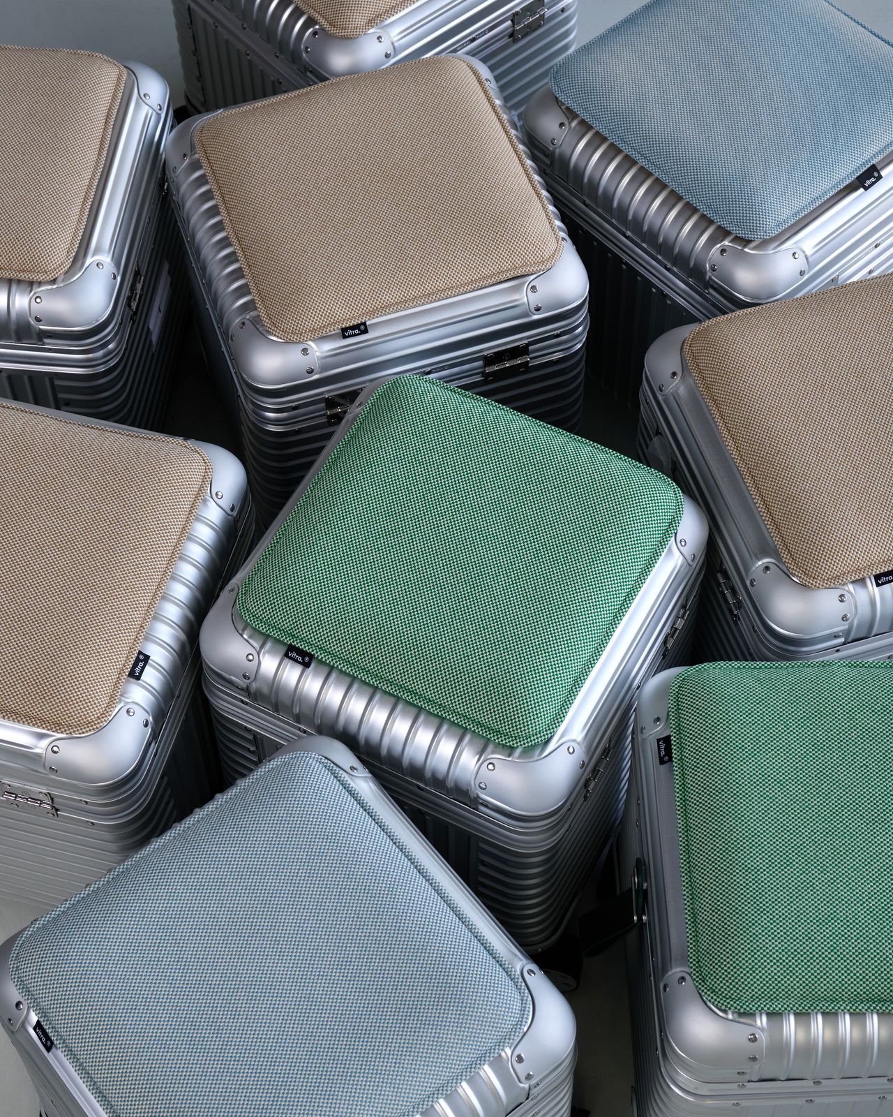 Birds-eye view of the RIMOWA x Vitra Aluminum Stool with cushions in three different colours: beige, spring green and ice blue