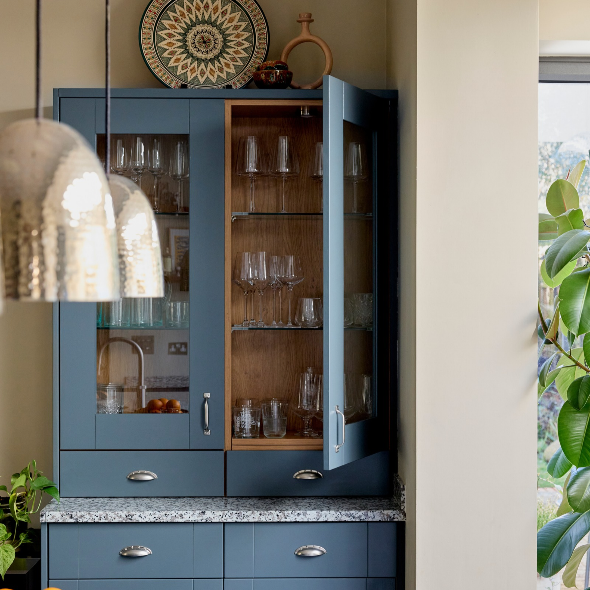 Blue cabinet with glasss front holding glassware and barware.