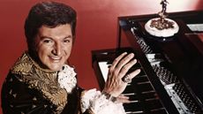 liberace playing piano in a red room