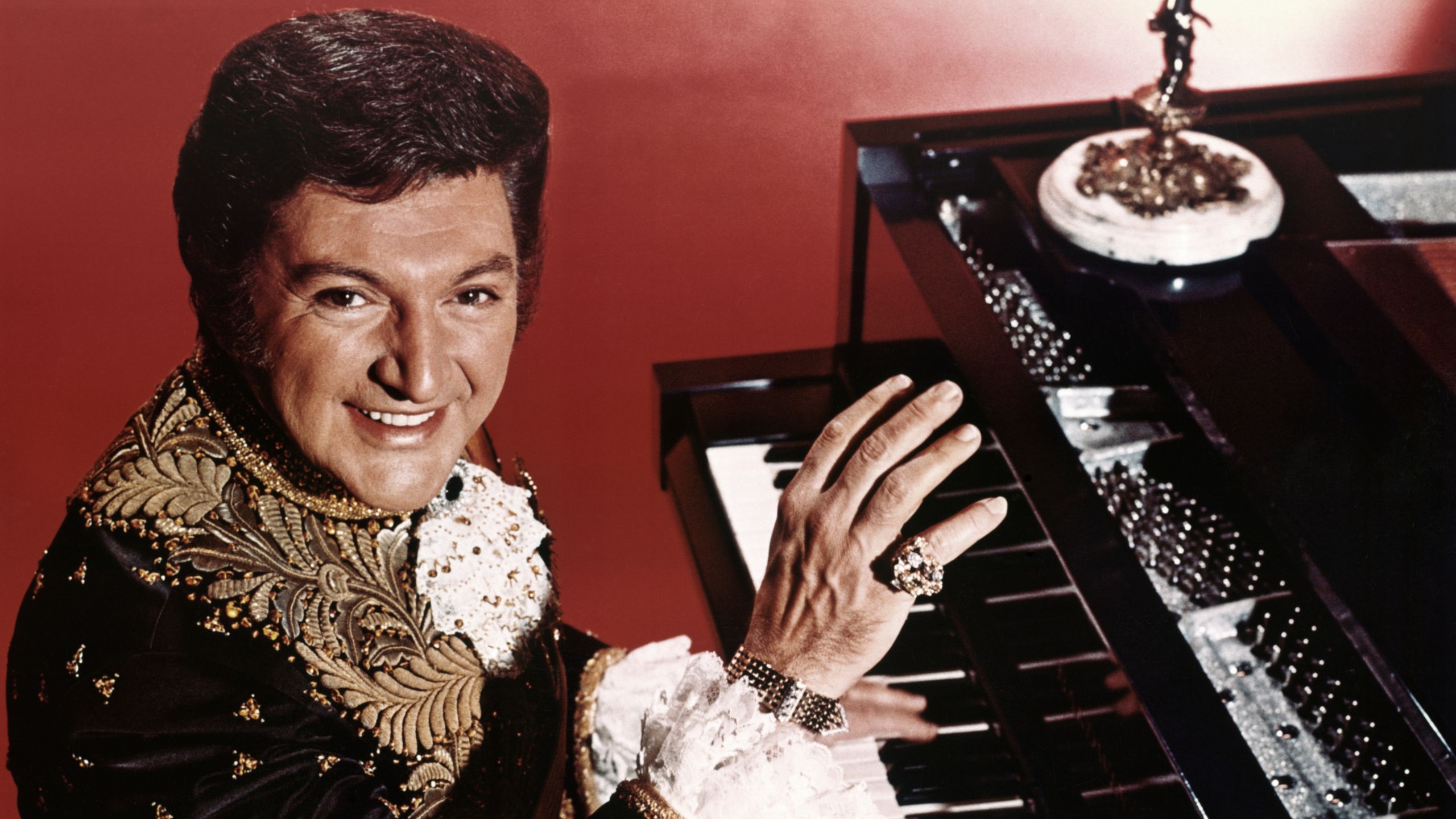 liberace playing piano in a red room