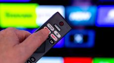 Philips TV remote pointed at television filled with apps