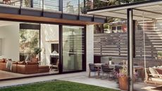 A garden with the view of the inside of the home's living room areas well as a view of a pergola and outdoor dining area with lots of patio furniture 