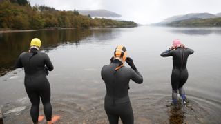 Open water swimmers wearing wetsuits getting ready to go swimming in a Scottish loch