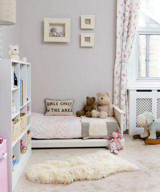 neutral kids room with patterned curtains, storage and faux fur rug