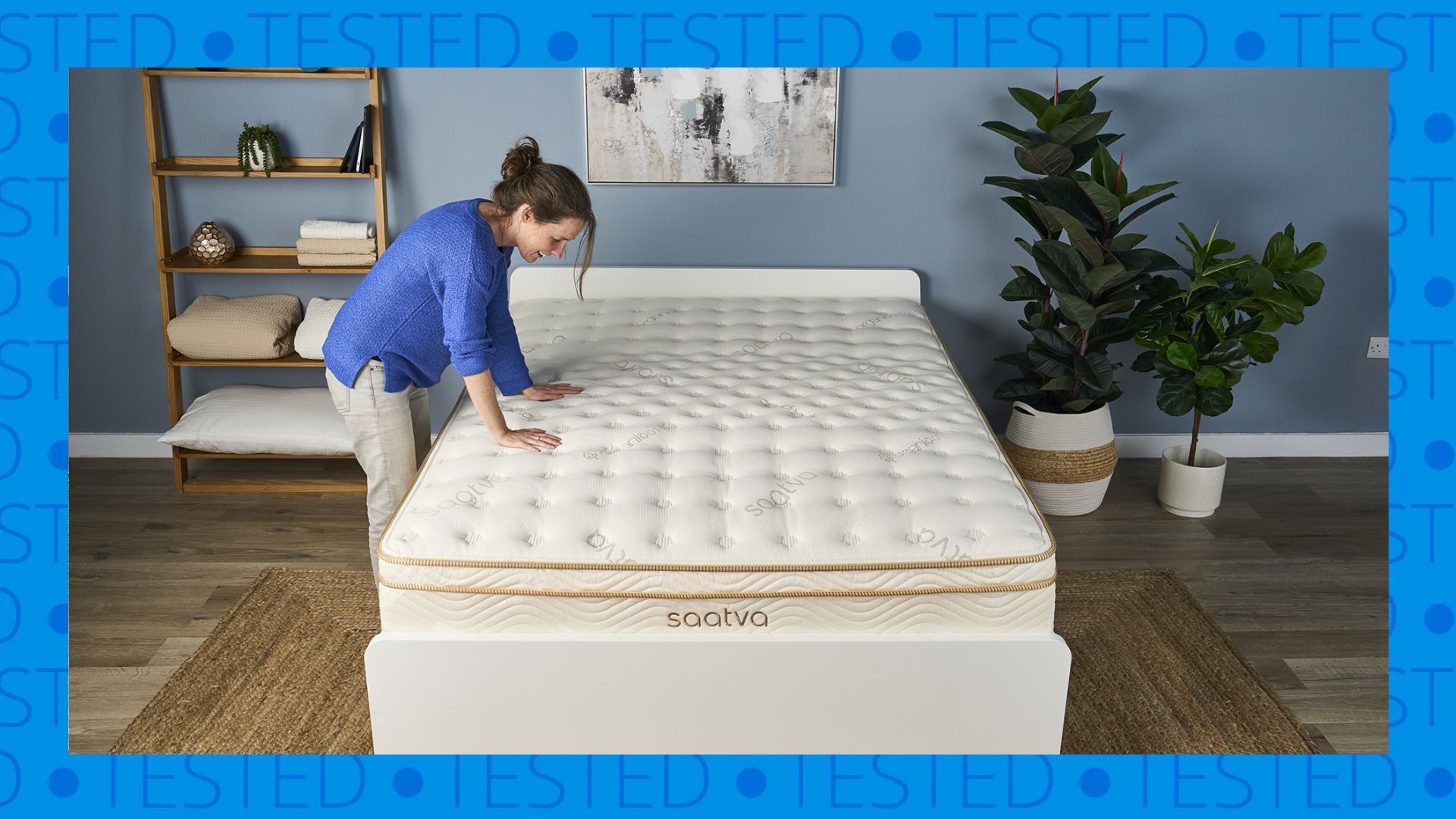The image shows a dark haired mattress tested placing her hands on the surface of a cream and gold mattress