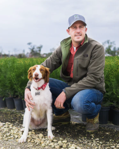 Man wearing grey cap crouching down with dog