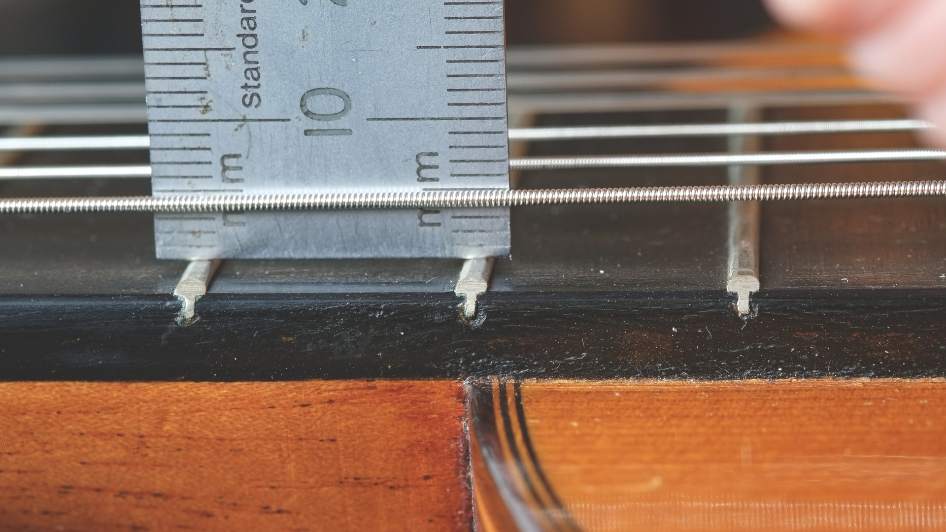 A ruler measuring the string action on a classical guitar