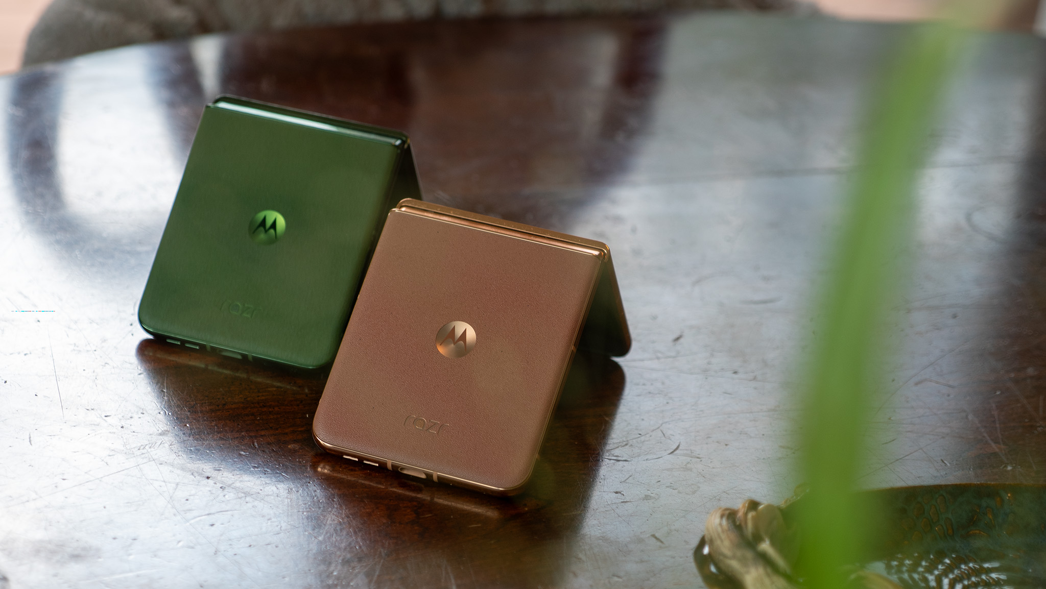 The folded backs of the Motorola Razr Plus 2024 in Green and Motorola Razr Plus 2025 in Mocha