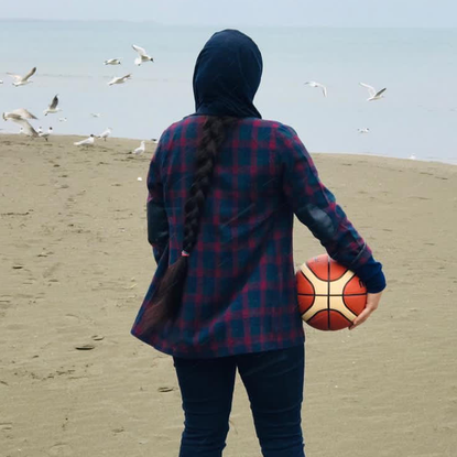 An Afghani basketball player looks out at the beach in Albania where she is living as a refugee