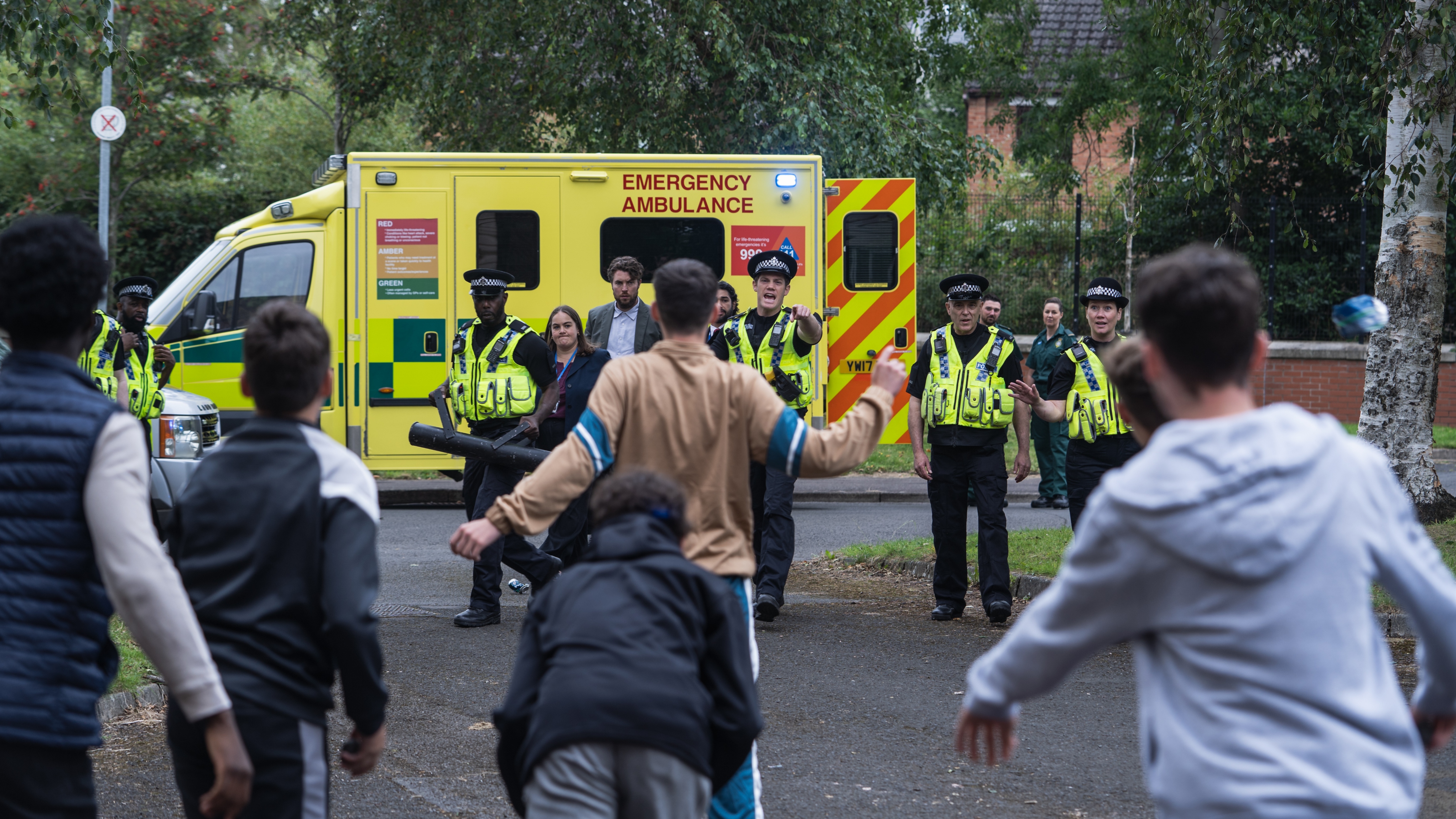 Pictured: TOM HUGHES as DR James Ford surrounded by police and protesters.
