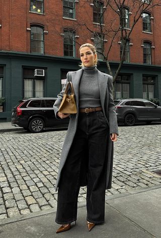 best black jeans is shown on a woman wearing a gray coat with a gray turtleneck and black wide-leg jeans and tan heels