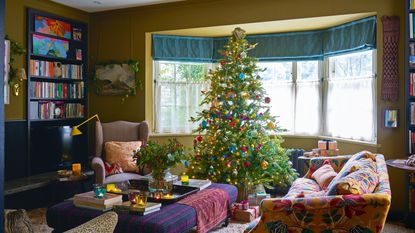 colorful and patterned living room with green walls, a bay window and a Christmas tree