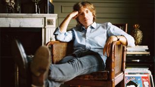 Nicolas Godin relaxing in a chair surrounded by vinyl