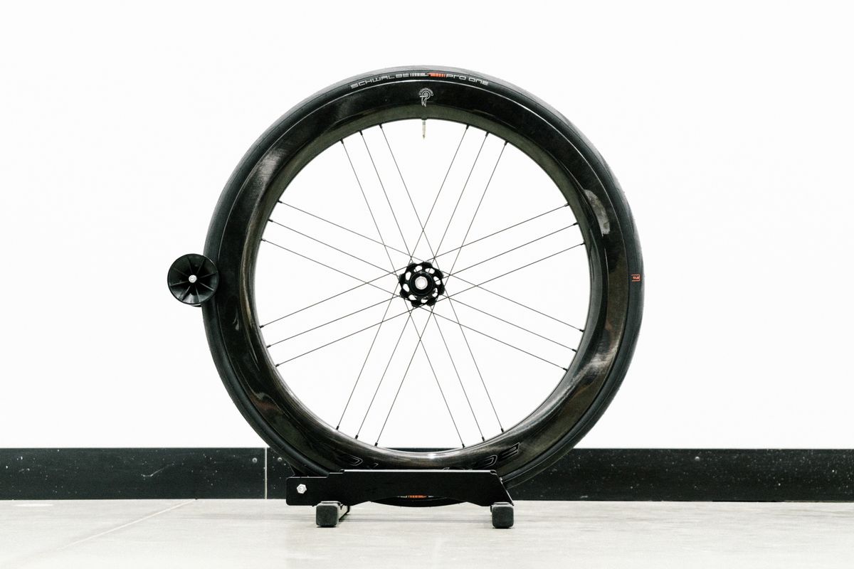 An aero road wheel stands against a white wall