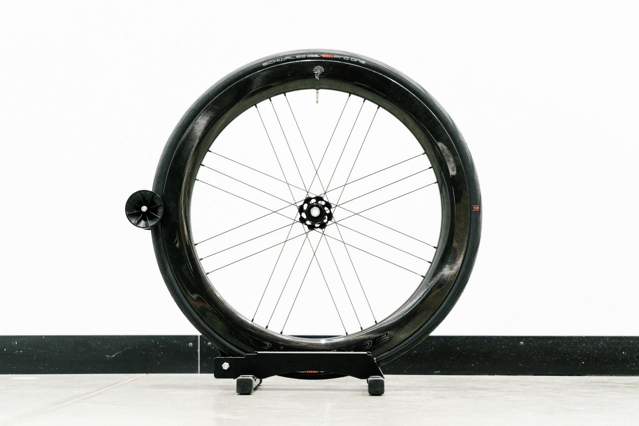 An aero road wheel stands against a white wall