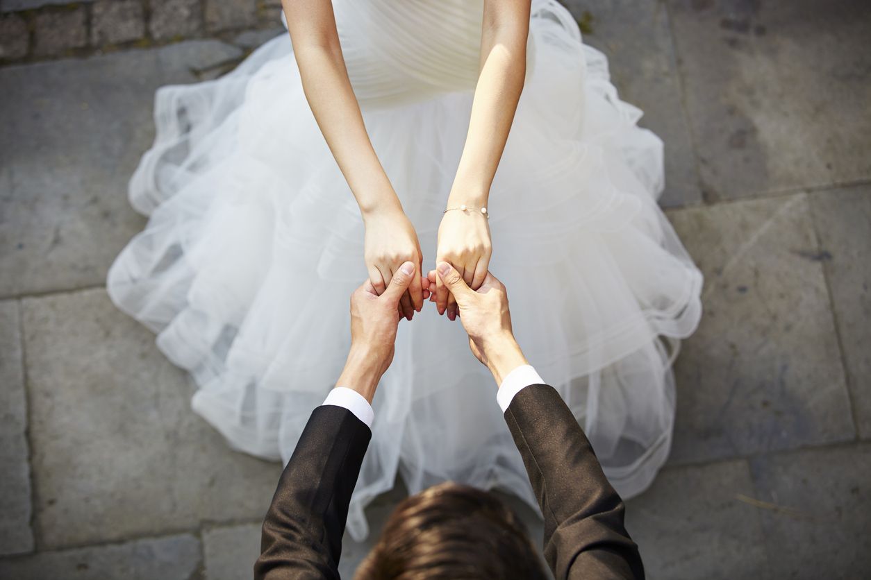 A bride and groom hold hands.