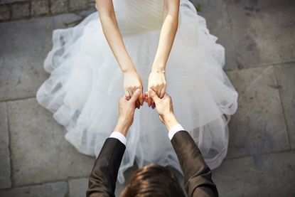 A bride and groom hold hands.