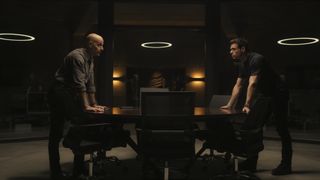 Bernard and Mason lean on the back of chairs in an office in Citadel on Prime Video