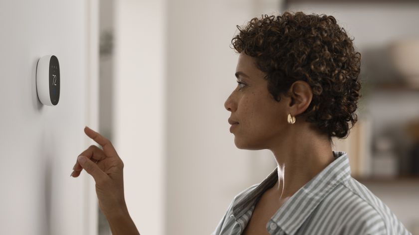 Woman using Ecobee Smart Thermostat Essential installed on wall