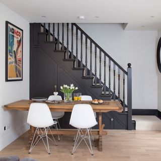 dining table and chairs next to black painted stairway