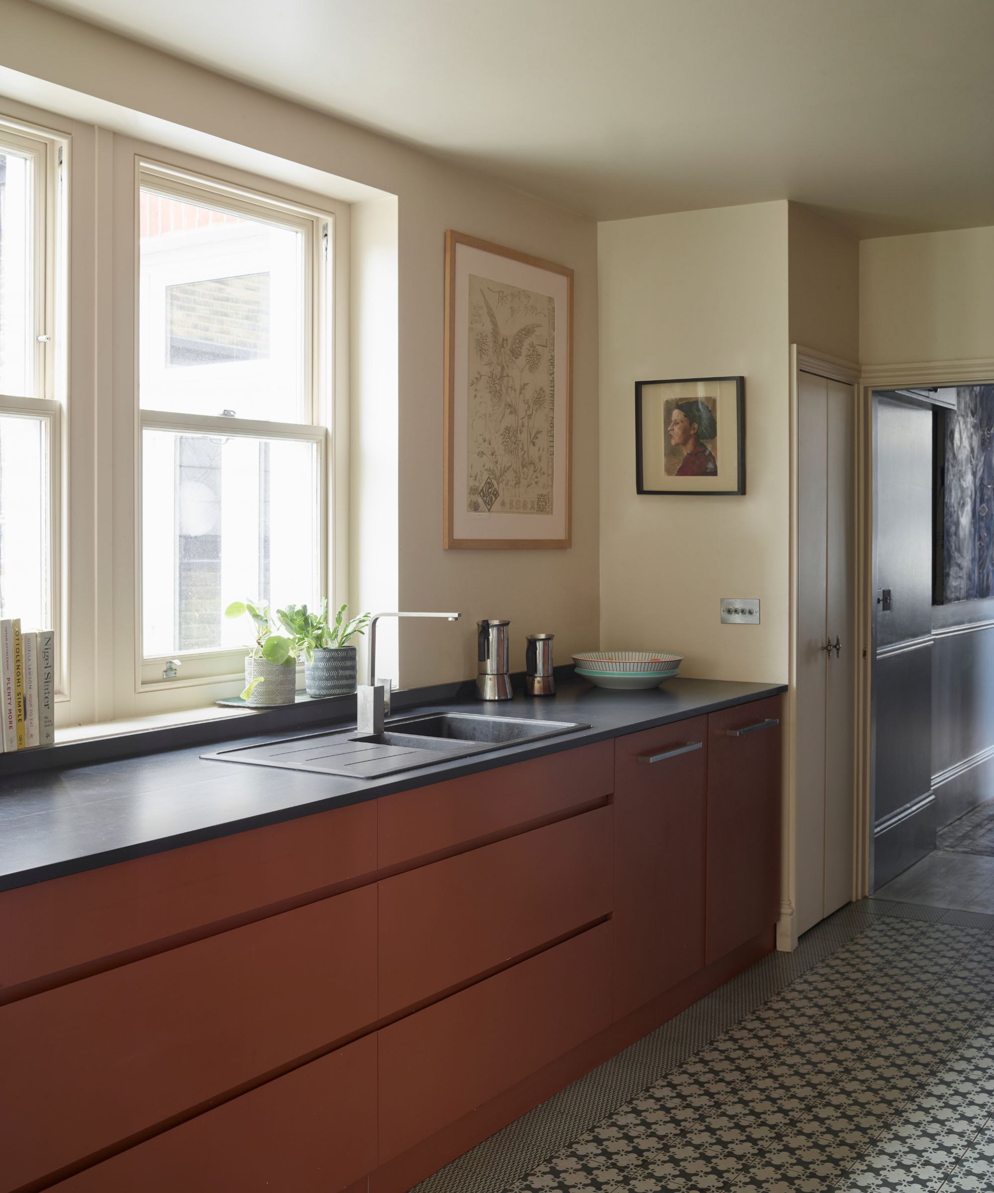 Galley kitchen with dark red slab doors and a black countertop with cream walls