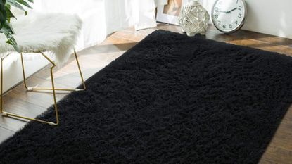 Black fluffy rug on room with white chair and curtains 
