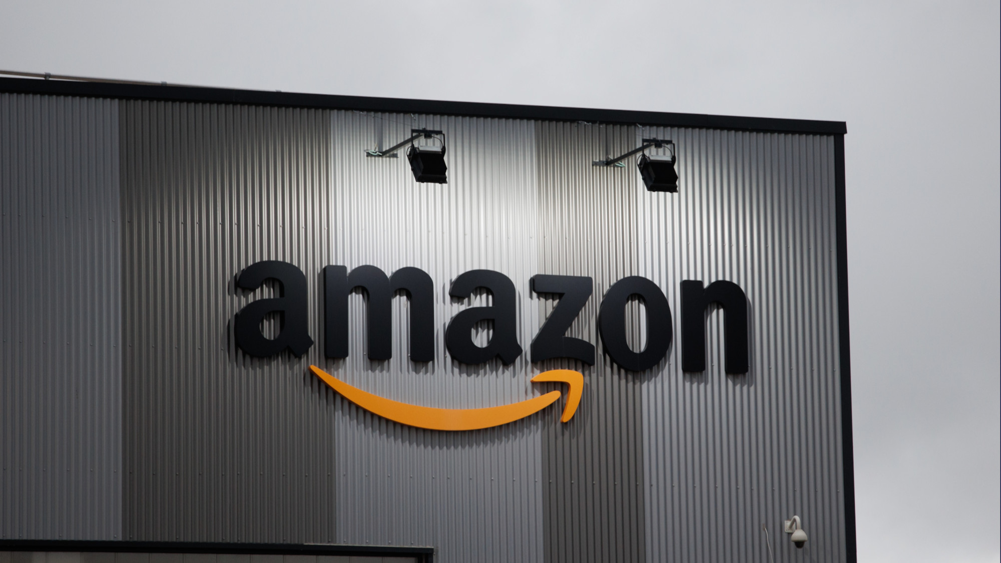 Amazon logo on the outside of a warehouse with cloudy sky