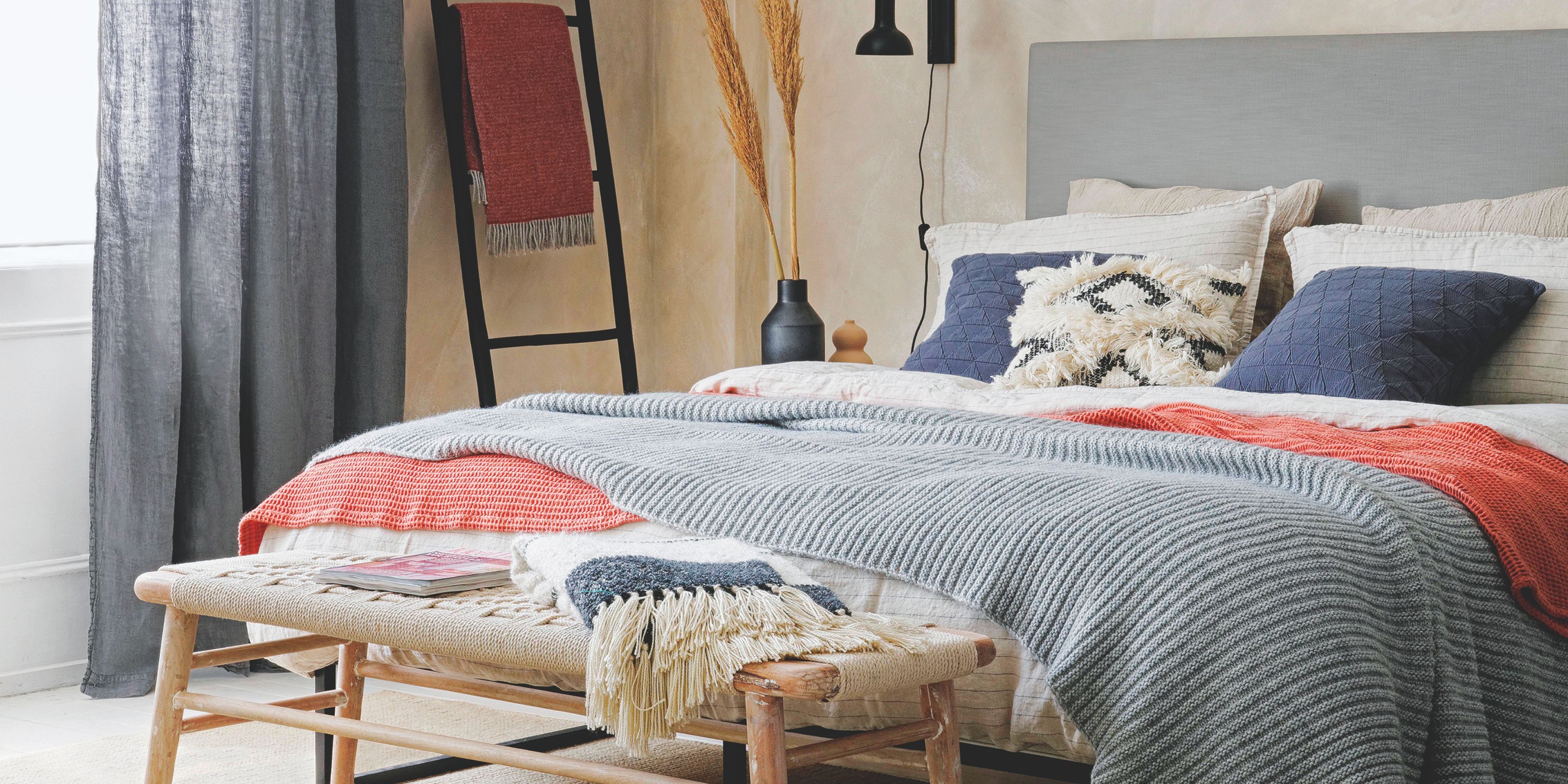 A scandi-style bedroom with layered bedding and cushions