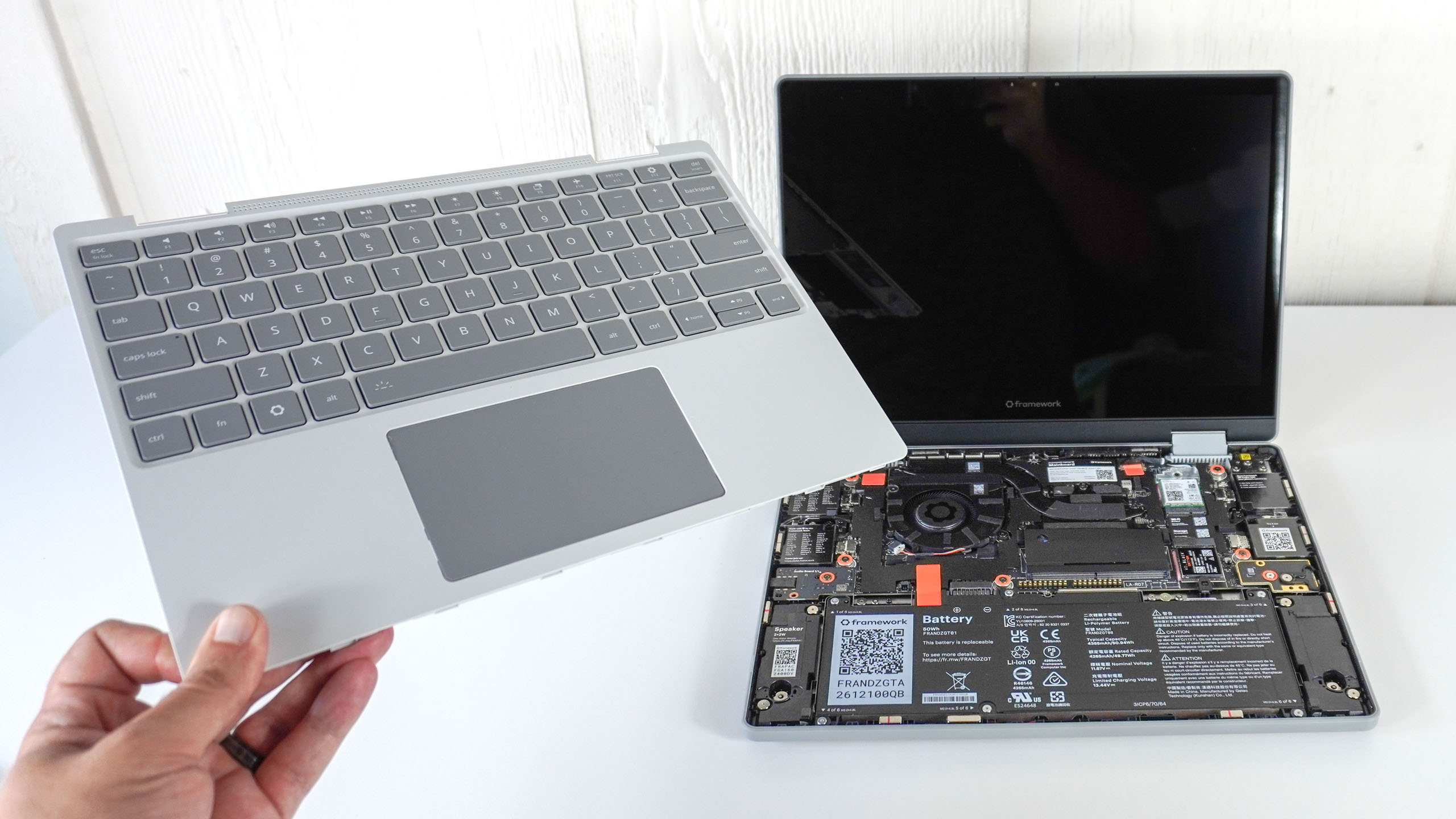 A person holding up the Input Cover for the Framework Laptop 12 in front of the laptop