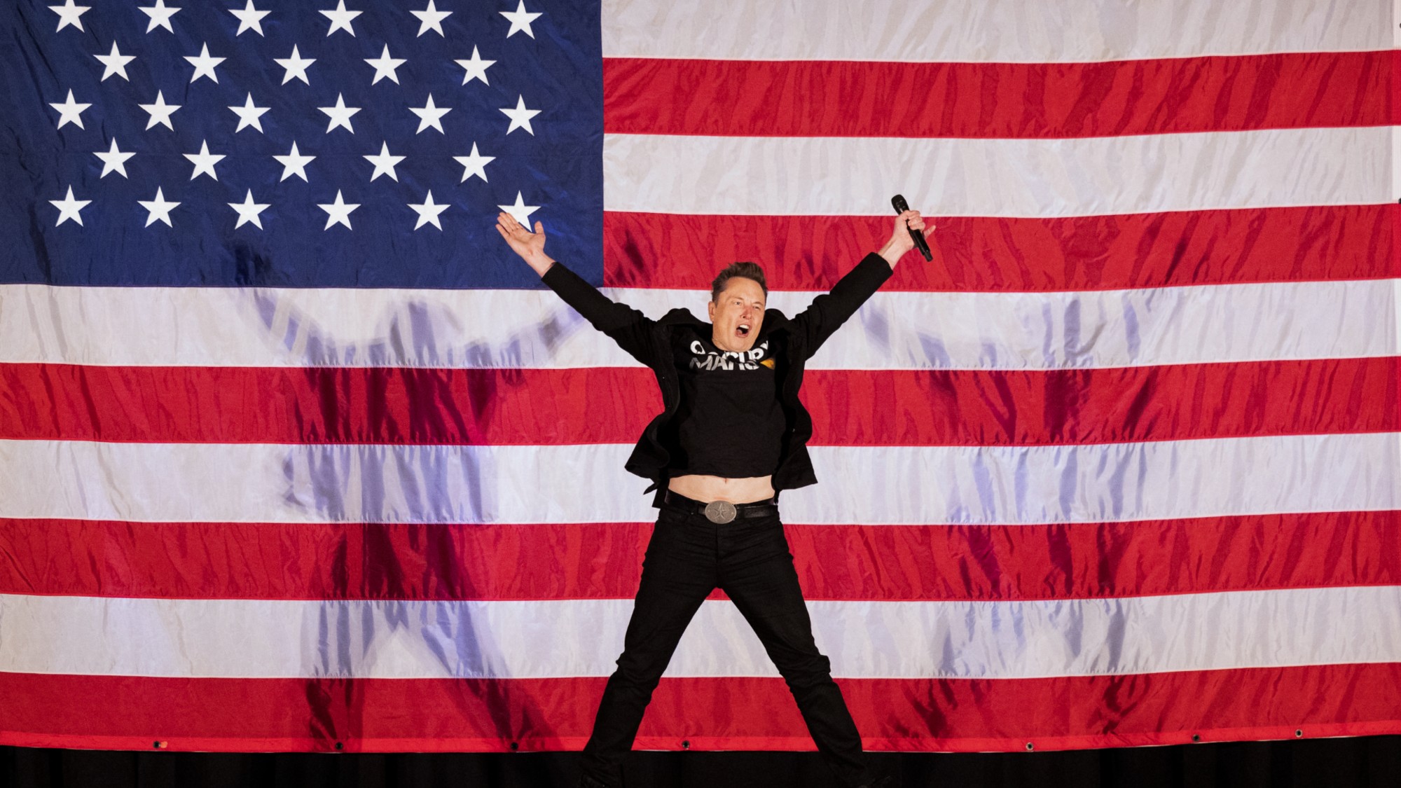 Elon Musk jumps on stage as he arrives to speak at a town hall event hosted by America PAC