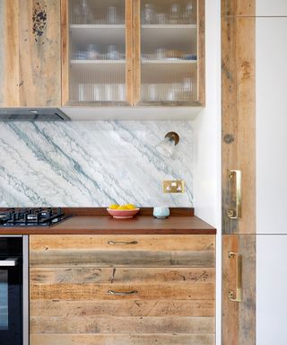 wooden kitchen with glazed cupboards and marble splashback