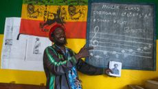 A teacher points to a blackboard in a school in Jamaica
