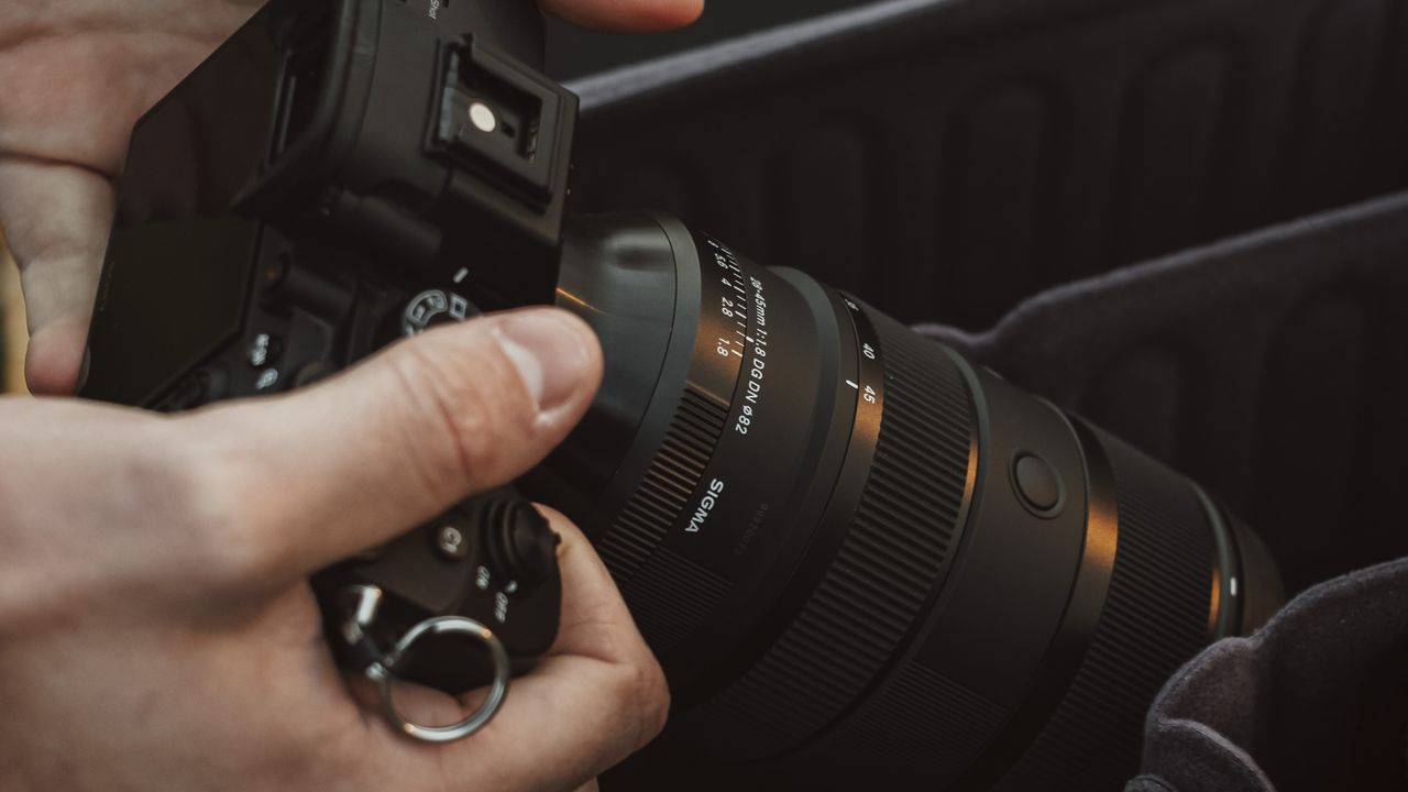 Sigma 28-45mm F1.8 lens mounted on a Sony camera being held by a photographer