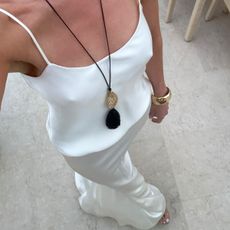 Woman wearing a long pendant necklace over a white outfit