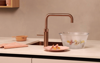 Quooker tap on a pink worktop with a bowl of dummies being sterilized in a bowl